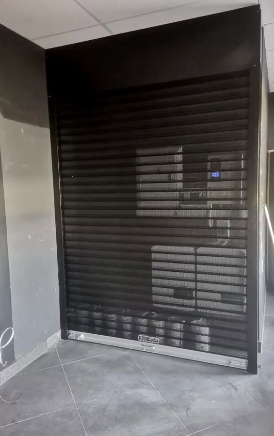 Black perforated roller shutter on a shopfront