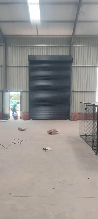 Charcoal roller shutter door inside a steel-framed warehouse