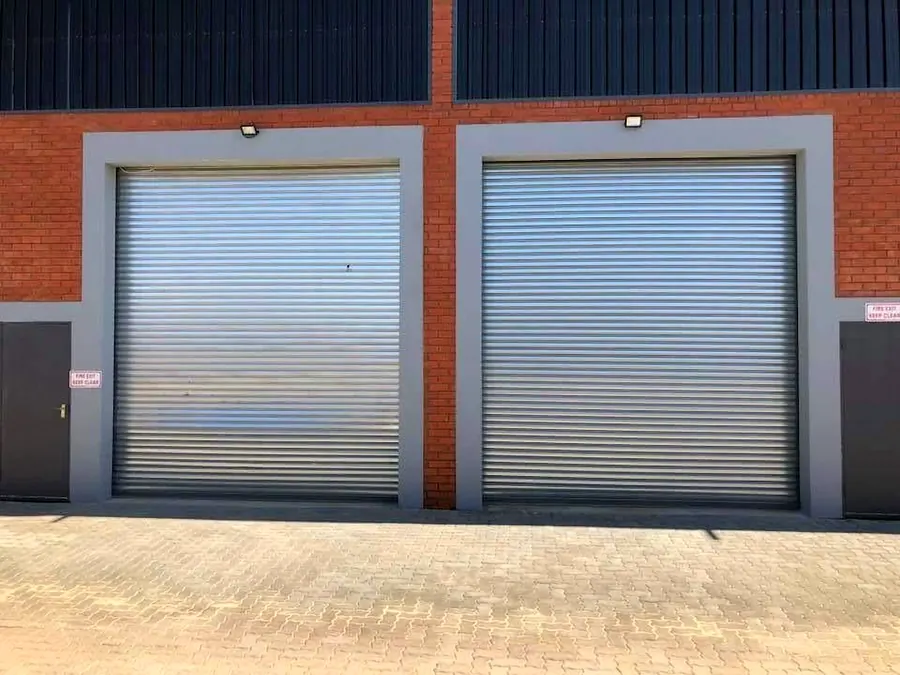 Two galvanised roller shutter doors on a face-brick industrial unit