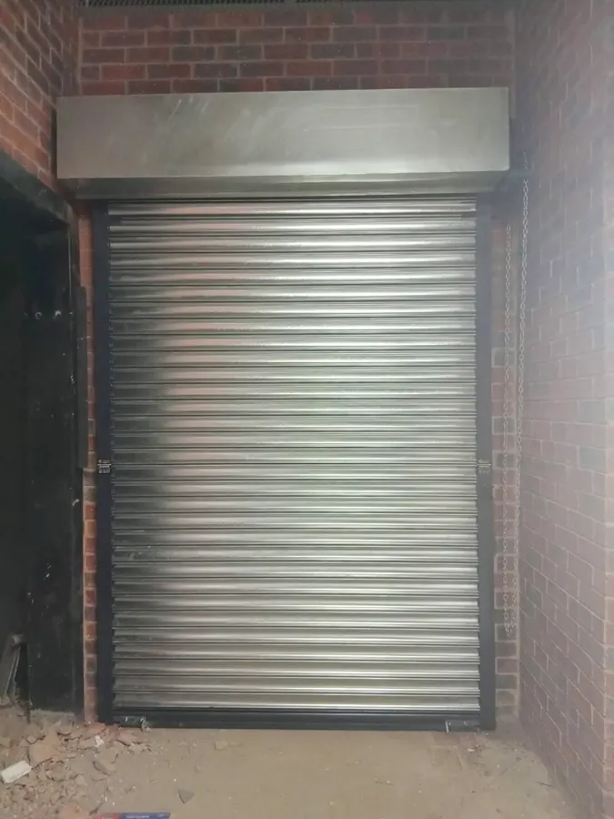 Galvanised roller shutter fitted into a brick recess with hood box