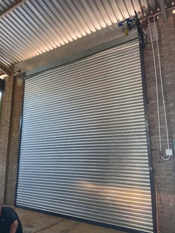 Galvanised roller shutter door with chain gear operation inside a brick warehouse