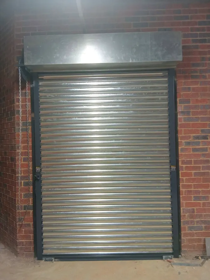 Galvanised roller shutter with hood on a face-brick wall