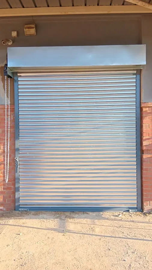Galvanised roller shutter door with hood cover on a brick building