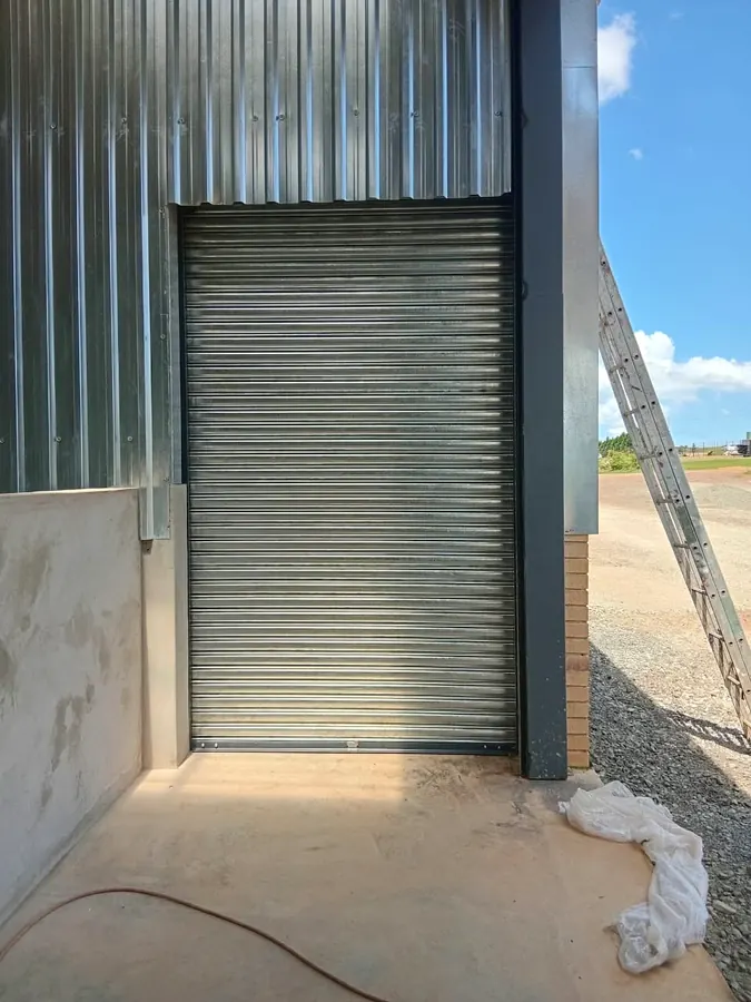 Tall galvanised roller shutter on a steel-clad building